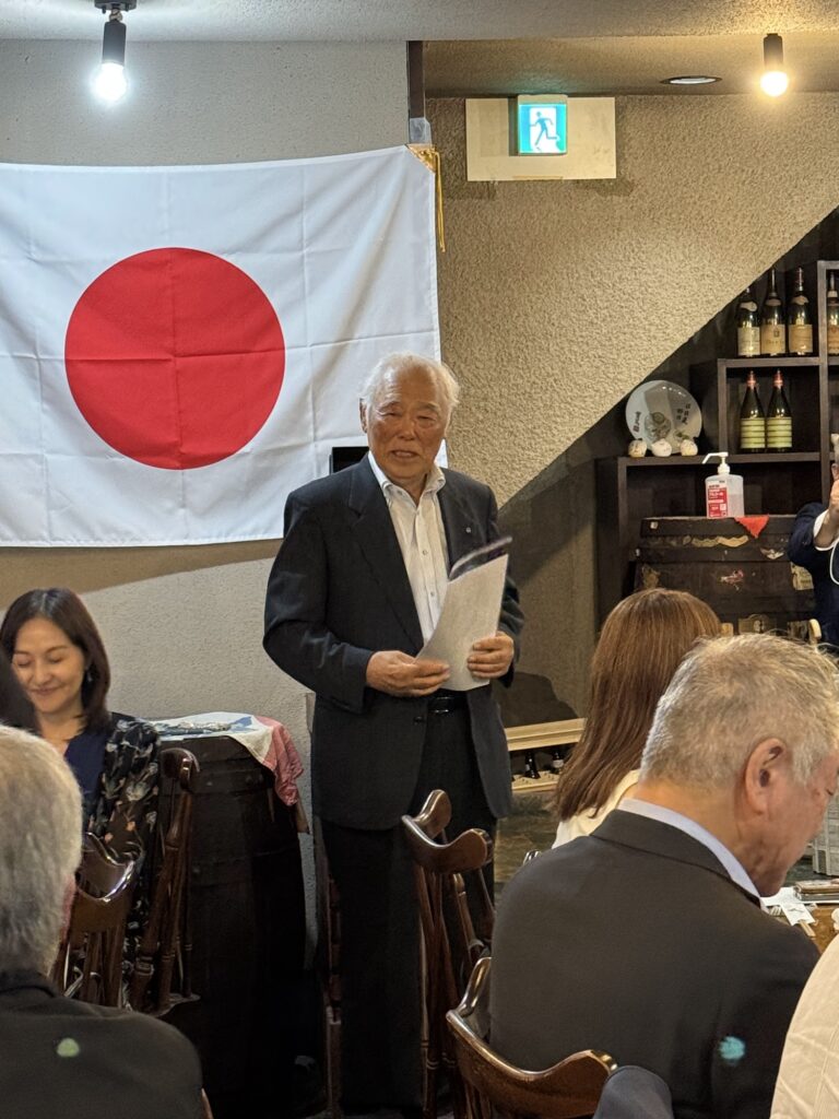 国旗の前でご挨拶をされる様子